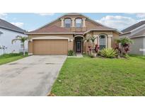 Charming home exterior with well-maintained landscaping and an attached two-car garage at 34447 Windknob Ct, Wesley Chapel, FL 33545