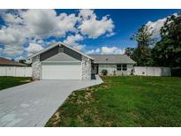 Charming single-story home with a paved driveway, two-car garage, stone accents, and a well-maintained lawn at 7547 Landmark Dr, Spring Hill, FL 34606