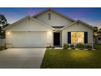 Charming single-story home featuring a two-car garage and manicured front lawn at dusk at 10452 Elgin Blvd, Spring Hill, FL 34608