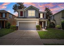 Two-story home featuring a two-car garage, well-maintained lawn, and lovely curb appeal at 13722 Lakemont Dr, Hudson, FL 34669