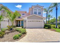 Charming two-story home featuring a two-car garage, tropical landscaping, and a welcoming blue front door at 1411 Tessano Pl, Palm Harbor, FL 34683