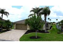 Well-maintained home featuring a manicured lawn, brick driveway, and lush landscaping with mature palm trees at 29435 Snap Hook Dr, San Antonio, FL 33576