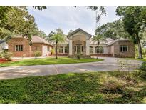 Sprawling brick home featuring a circular driveway and manicured lawn at 3042 Oak Creek N Dr, Clearwater, FL 33761
