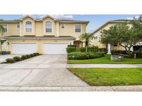 Charming two-story townhouse featuring a two-car garage, well-maintained lawn, and vibrant landscaping at 3484 Primrose Way, Palm Harbor, FL 34683