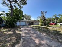 Inviting single-story home with a driveway and attached garage surrounded by lush greenery at 422 Crosswinds Dr, Palm Harbor, FL 34683