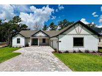 Charming single-story home featuring a brick driveway, attached garage, well-manicured lawn, and classic architectural design at 4799 Hickory Oak Loop, Brooksville, FL 34601