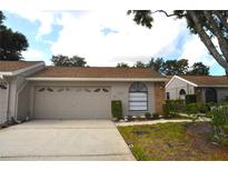 Charming single-story home with a beige exterior, two car garage and well-maintained landscaping at 5530 Salem Square N Dr, Palm Harbor, FL 34685