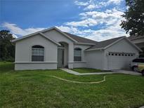 Charming single-story home featuring a well-manicured lawn, arched windows, and an attached two-car garage at 10621 Ribbon Fern Way Way, Land O Lakes, FL 34638