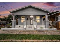 Charming single-story home with a welcoming front porch and a well-maintained lawn under an expressive sky at 1902 N Tampania Ave, Tampa, FL 33607