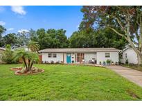 Charming single-story home with a well-manicured lawn, a bright blue front door, and mature trees at 670 42Nd Ne Ave, St Petersburg, FL 33703