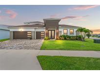 Stunning two-story home featuring a three-car garage, paver driveway, and beautifully manicured lawn at 8752 Loft Pt, Wesley Chapel, FL 33545