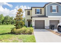 Charming townhome showcasing a well-manicured lawn, two car garage, and inviting facade under a blue sky at 17592 Nectar Flume Dr, Land O Lakes, FL 34638