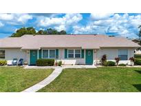 Charming attached villa featuring a well-maintained lawn, walkway and a turquoise front door at 1906 Canterbury Ln # 20, Sun City Center, FL 33573