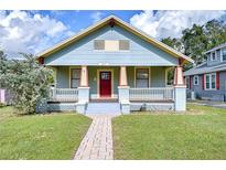 Charming single-story home showcasing a covered front porch and a well-maintained lawn, with a brick walkway at 205 W Emma St, Tampa, FL 33603