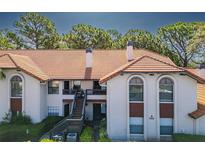 Charming condo with a red tile roof, stucco walls, and a inviting balcony, surrounded by lush green landscaping at 2640 Enterprise E Rd # B25, Clearwater, FL 33759