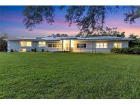 Stunning home exterior at twilight with a large front lawn and solar panels at 3425 W Forest Lake Cir, Sarasota, FL 34232