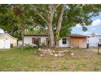 Charming single-story home featuring wood shutters and a stone-ringed tree in a lush front yard at 4650 87Th N Ter, Pinellas Park, FL 33782