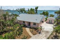 Charming waterfront home with lush landscaping, a concrete driveway, and a detached garage at 4749 Baywood Point S Dr, Gulfport, FL 33711