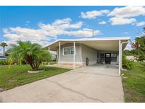 Charming single-story home featuring a covered carport, well-maintained lawn, and a beautiful palm tree at 5451 Antigua Dr, Zephyrhills, FL 33541