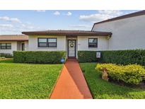 Charming single-story home with manicured lawn, tidy hedges, and a welcoming walkway to the front door at 7923 Radcliffe Cir, Port Richey, FL 34668