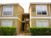 Inviting two-story exterior of a tan condo with a well-maintained front landscape at 9481 Highland Oak Dr # 1310, Tampa, FL 33647