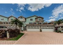 Beautiful townhouses with multi-car garages, brick driveway, manicured shrubs and palm trees, under blue skies at 1710 Lago Vista Blvd, Palm Harbor, FL 34685