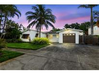 Charming single-story home with tropical landscaping, a driveway, and a one-car garage at 1720 Bayou Grande Ne Blvd, St Petersburg, FL 33703