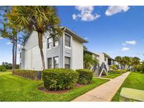 Inviting condo building featuring well-maintained landscaping, and a clear blue sky at 1967 Cormorant Ct # 515, Clearwater, FL 33762
