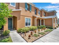 Inviting townhome featuring colorful landscaping, a teal front door, and complementary window shutters at 2007 Searay Shore Dr, Clearwater, FL 33763