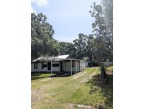 Modest home with covered porch and large trees creating a shaded yard at 2414 S 67Th St, Tampa, FL 33619