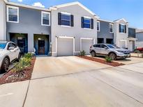 An exterior of townhomes featuring attached garages and modern design elements at 32977 Kaloko Rd, Wesley Chapel, FL 33543