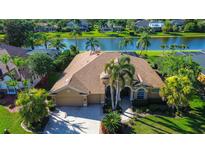 Stunning waterfront home featuring a tile roof, two-car garage, lush landscaping, and palm trees at 3895 Mimosa Pl, Palm Harbor, FL 34685