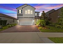 Charming two-story home with landscaped yard, brick driveway, two-car garage, and neutral gray paint at 4077 Cadence Loop, Land O Lakes, FL 34638