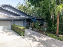 Charming home featuring a well-maintained lawn and an attached two-car garage, nestled among mature trees and landscaping at 70 Morning Dove Pl, Oldsmar, FL 34677