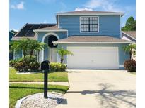 Charming two-story home featuring a manicured lawn, two car garage and vibrant landscaping with palm trees at 11121 Clayridge Dr, Tampa, FL 33635