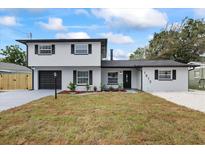 Two-story home featuring black trim, a black garage door, new landscaping, and a well-manicured lawn at 1413 E 108Th Ave, Tampa, FL 33612