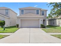 Charming two-story home features a two-car garage, well-maintained lawn, and neutral color scheme at 14403 Dunrobin Dr, Wimauma, FL 33598