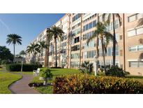 Well manicured multi-story building on a grassy lot, with tropical trees and beautiful landscaping at 1847 Shore Drive S # 415, South Pasadena, FL 33707