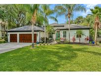Beautiful single-story home boasting mature landscaping, palm trees, a charming blue entry door, and a two-car garage at 2435 Fox Forest Dr, Lutz, FL 33549