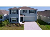 Charming two-story home with gray siding, dark shutters, well-maintained landscaping, and an attached two-car garage at 5470 Flint Hills Dr, Wimauma, FL 33598