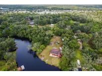 Aerial view of a home surrounded by lush trees, waterways, and a serene lake nearby at 5832 Portal Rd, New Port Richey, FL 34655