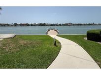Beautiful waterfront with a path leading to a private dock overlooking tranquil waters and distant buildings at 750 Island Way # 101, Clearwater Beach, FL 33767