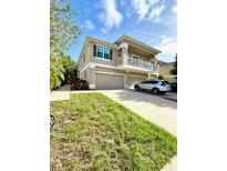 Two-story townhome with a front-facing two-car garage, balcony, and well-manicured lawn at 7543 Red Mill Circle Cir, New Port Richey, FL 34653