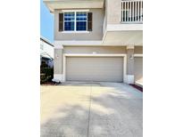 Two-car garage featuring a light-colored door, tan stucco exterior, and well-maintained driveway at 7543 Red Mill Circle Cir, New Port Richey, FL 34653