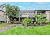 A charming condo with two stories, covered balconies, green grass, and mature trees, and the exterior has a neutral color palette at 10265 Gandy N Blvd # 1702, St Petersburg, FL 33702