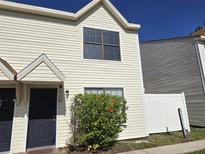 Two-story home with cream siding, dark blue door, and a garden with red flowers in front at 2302 Maki Rd # 2, Plant City, FL 33563