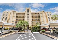 Multi-story condo building featuring balconies, palm trees, and covered parking at 2621 Cove Cay Dr # 302, Clearwater, FL 33760