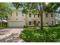 Two-story home with tan stucco, red tile roof, arched entry and brick driveway with mature landscaping at 2900 W Estrella St, Tampa, FL 33629