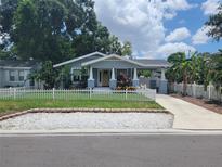 Charming single-story home featuring a cute picket fence and a covered carport on a sunny day at 318 W Crest Ave, Tampa, FL 33603