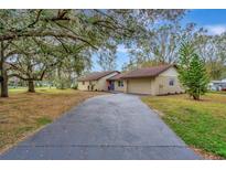 Charming single-story home with long driveway and mature trees on a large lot at 5749 Southernview Dr, Zephyrhills, FL 33541